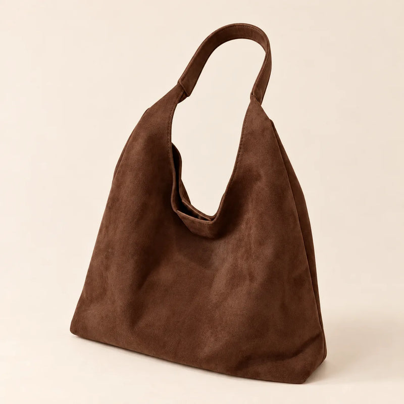Coffee faux suede shoulder bag with a single fixed strap on a sand background