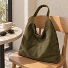 Olive Green faux suede shoulder bag on a wooden cafe chair